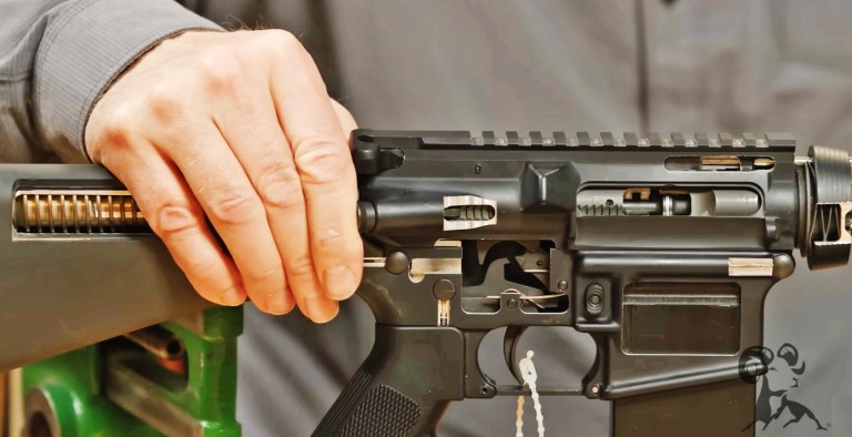 Brownells demonstrating the use of a forward assist on a cutaway model. 