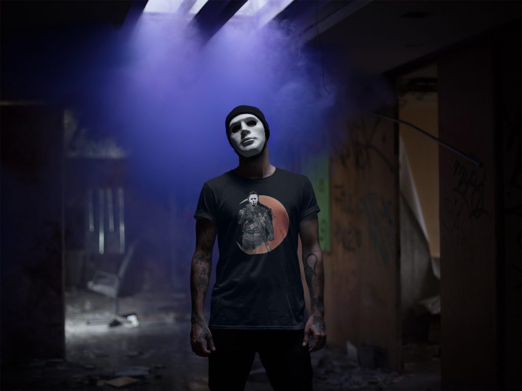 It's a tactical Halloween theme inception moment. A guy in a mask wearing a men's Halloween shirt with the most famous mask of all on it: the Michael Myers mask. Check out the Michael Myers shirt for Halloween 2025.